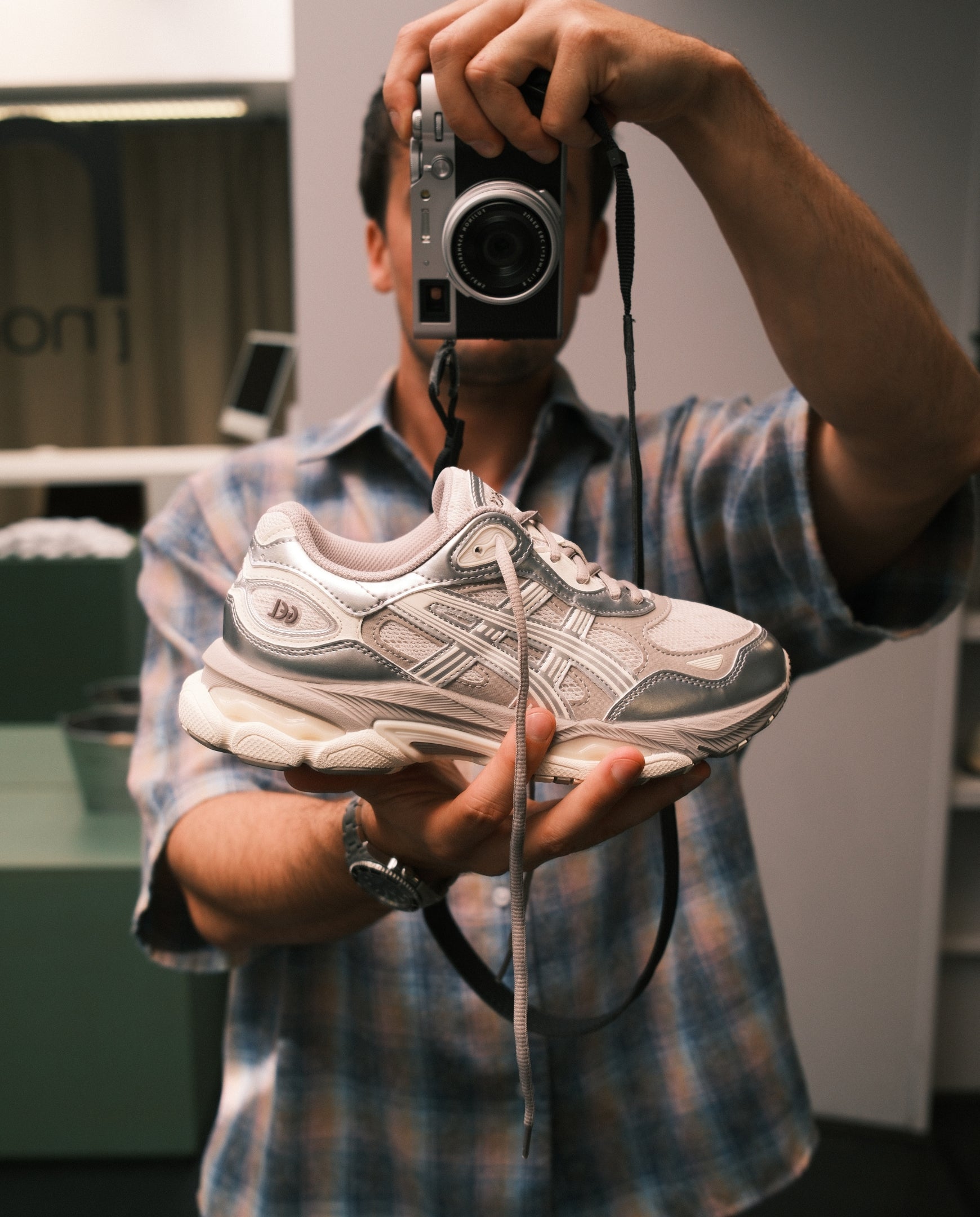 ASICS Gel-NYC 2.0 sneaker vastgehouden, smoke grey en zilver, close-up met veters