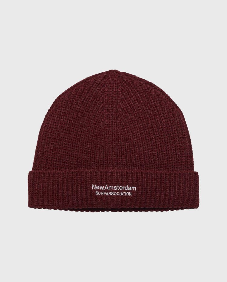 Reversibele beanie donkerrood met NewAmsterdam-logo op geribde boord.