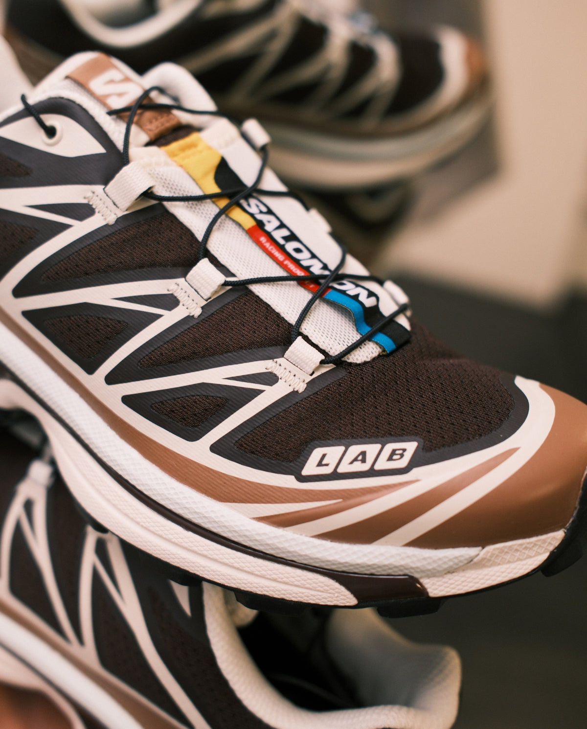 Salomon XT-6 vetersluiting, bruine tong, gekleurde veters en witte zijpanelen.