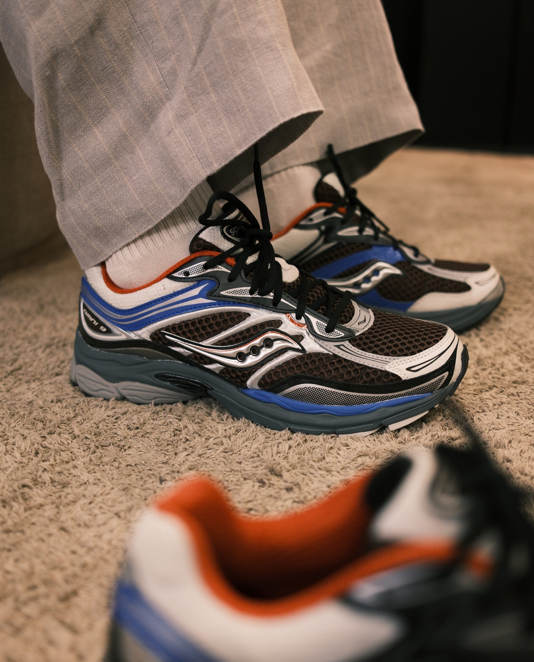Saucony hardloopschoenen met zwart-wit mesh, blauwe tussenzool en oranje hiel