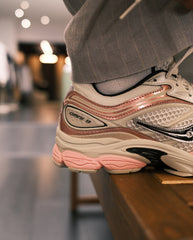 Saucony sneakerzijkant in lichtbeige met roze bies, Omni-logo en zwart detail