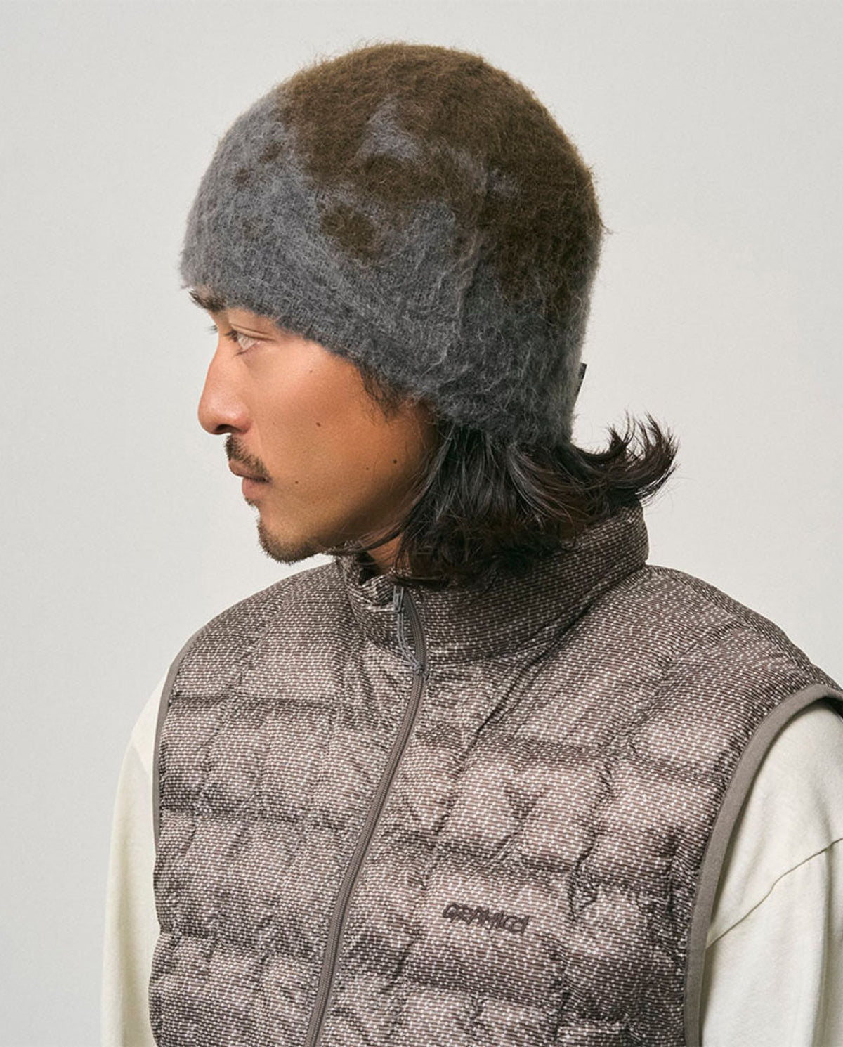 Donkere grijze beanie met spetterpatroon, gedragen over de zijkant van het hoofd