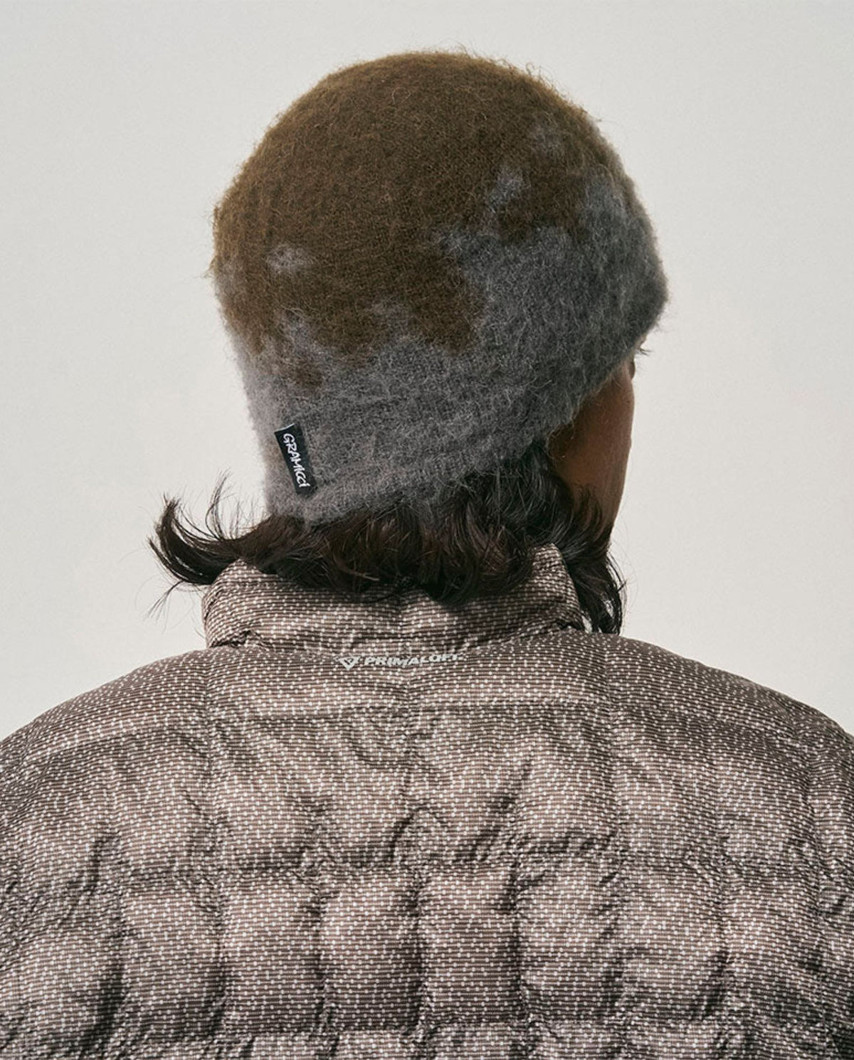 Donkere grijze beanie met spetterpatroon, met merklabel aan de achterkant