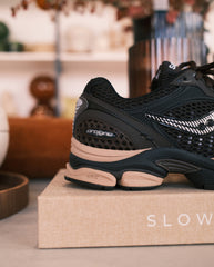 Hardloopschoen met zwarte mesh, zijlogo en lichtroze zool op beige verpakking
