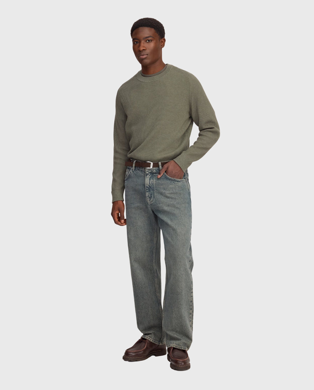 Blauwe stonewash jeans met rechte pijpen en riemlussen, gedragen met leren laarzen.